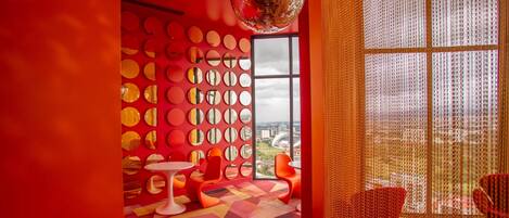 A vibrant room with a geometric patterned carpet, a disco ball, and a wall adorned with circular mirrors.