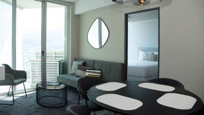 Ein modernes Hotelzimmer mit Balkon, einem runden Esstisch, einer Couch und einem großen Spiegel.