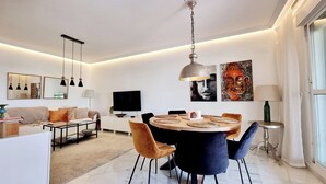 Una sala de estar moderna con comedor, televisor de pantalla plana y obras de arte en las paredes.
