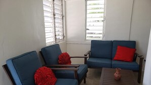 Una habitació amb dos sofàs blaus, un amb un coixí vermell, i una taula de fusta petita amb una olla de fang.