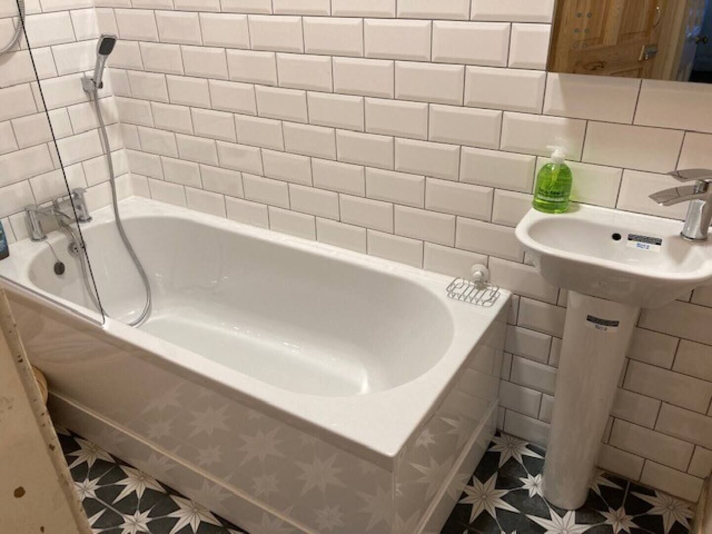 A bathroom with a white bathtub, a sink, and a mirror.