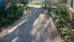 A gravel driveway leading to a garage with a house on the left and a shed on the right. - Central Location  Beach Access BBQ  Patio Cottage (Long Beach)