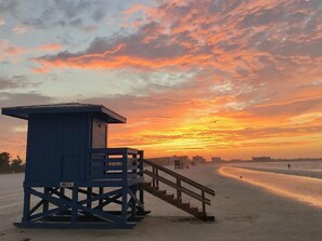 A lifeguard tower on a beach with a sunset in the background.