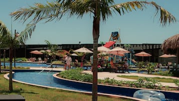 Un área de piscina con agua cristalina, palmeras y sillas de descanso.