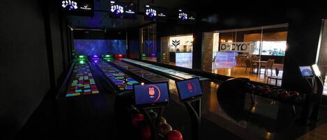 A bowling alley with multiple lanes, a seating area, and a counter.