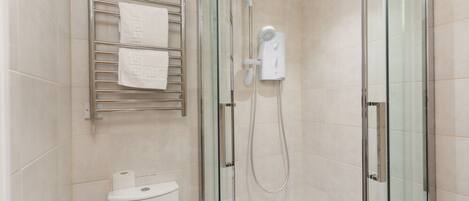 Une salle de bain moderne avec une douche à parois de verre, des toilettes et un porte-serviettes.