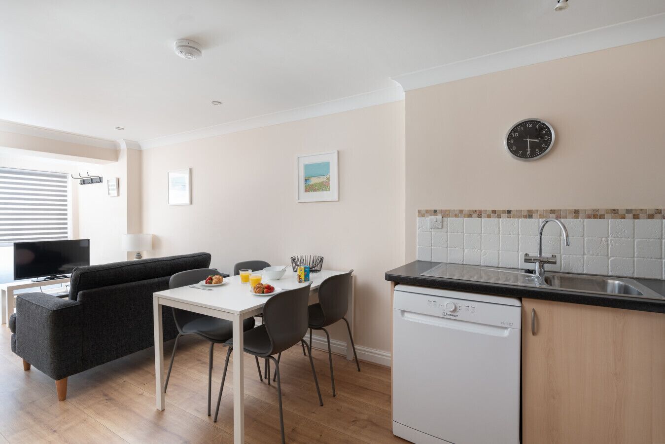 A compact kitchen with a dishwasher, a sink, and a dining area with a table and chairs.