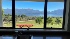 A kitchen with a large window overlooking a lake and mountains.