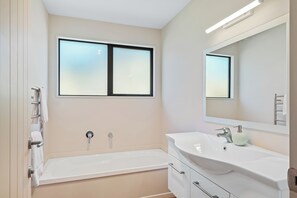 Ein modernes Badezimmer mit Badewanne, Waschbecken und Spiegel.