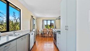 Une cuisine moderne avec un coin repas, de grandes fenêtres et une vue sur la verdure.