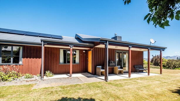 Une maison moderne dotée d’un patio couvert, de grandes fenêtres et de panneaux solaires.
