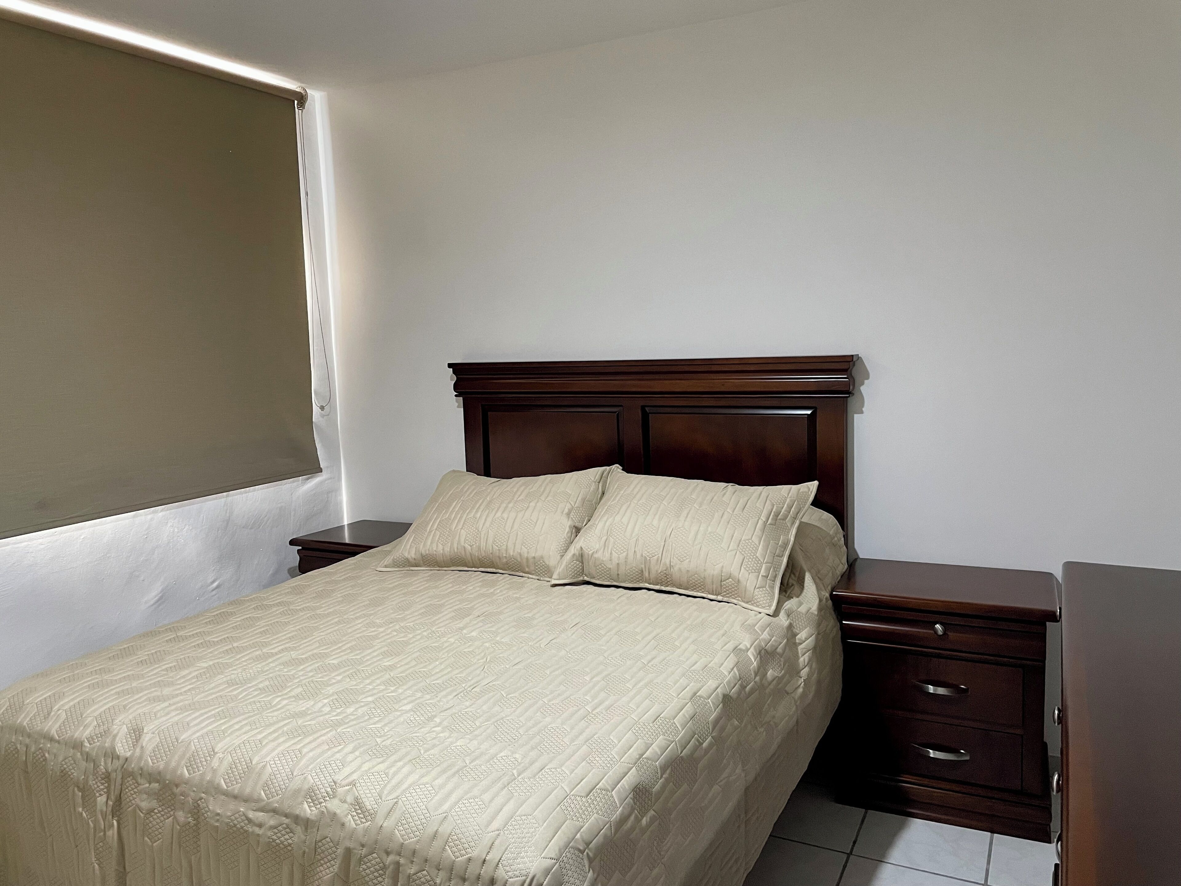 Ein Schlafzimmer mit einem hölzernen Bett, zwei Nachttischen und einer Kommode.