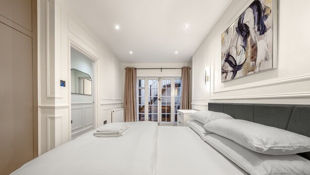 A hotel room with a large bed, a wardrobe, a mirror, and a view of the outside. - Pimlico Brand New Luxury Home (London)