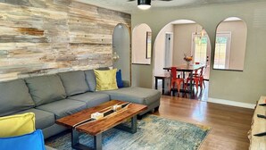 A living room with a sofa, coffee table, and a dining area with chairs and a table. - Ultimate Furnished Rental-Centrally Located (Aurora)
