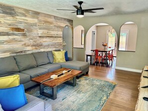A living room with a sofa, coffee table, and a dining area with chairs and a table.