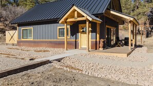 Une cabane avec un toit en métal, un revêtement extérieur en bois et une véranda.