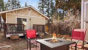 Eine Terrasse mit Feuerstelle, Sitzgelegenheiten im Freien und einer überdachten Veranda.