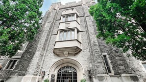 A historic stone building with a large arched entrance, a prominent clock tower, and a sign indicating it is a college. - Knox Residence University of Toronto (Toronto)