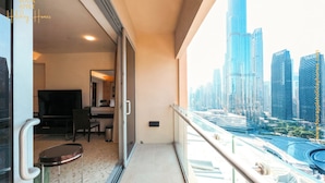 A balcony with a city view, a small seating area, and a desk with a chair. - Lovely Studio Burj Khalifa View (Dubai)