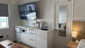 A modern kitchen with a flat-screen TV, a coffee maker, and a sink. - BeachFront On The Sand Unit #326 South of 5th, 335 Ocean Dr, Miami Beach (Miami Beach)