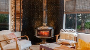 Un salon chaleureux avec un mur en pierre, une cheminée et des sièges confortables.