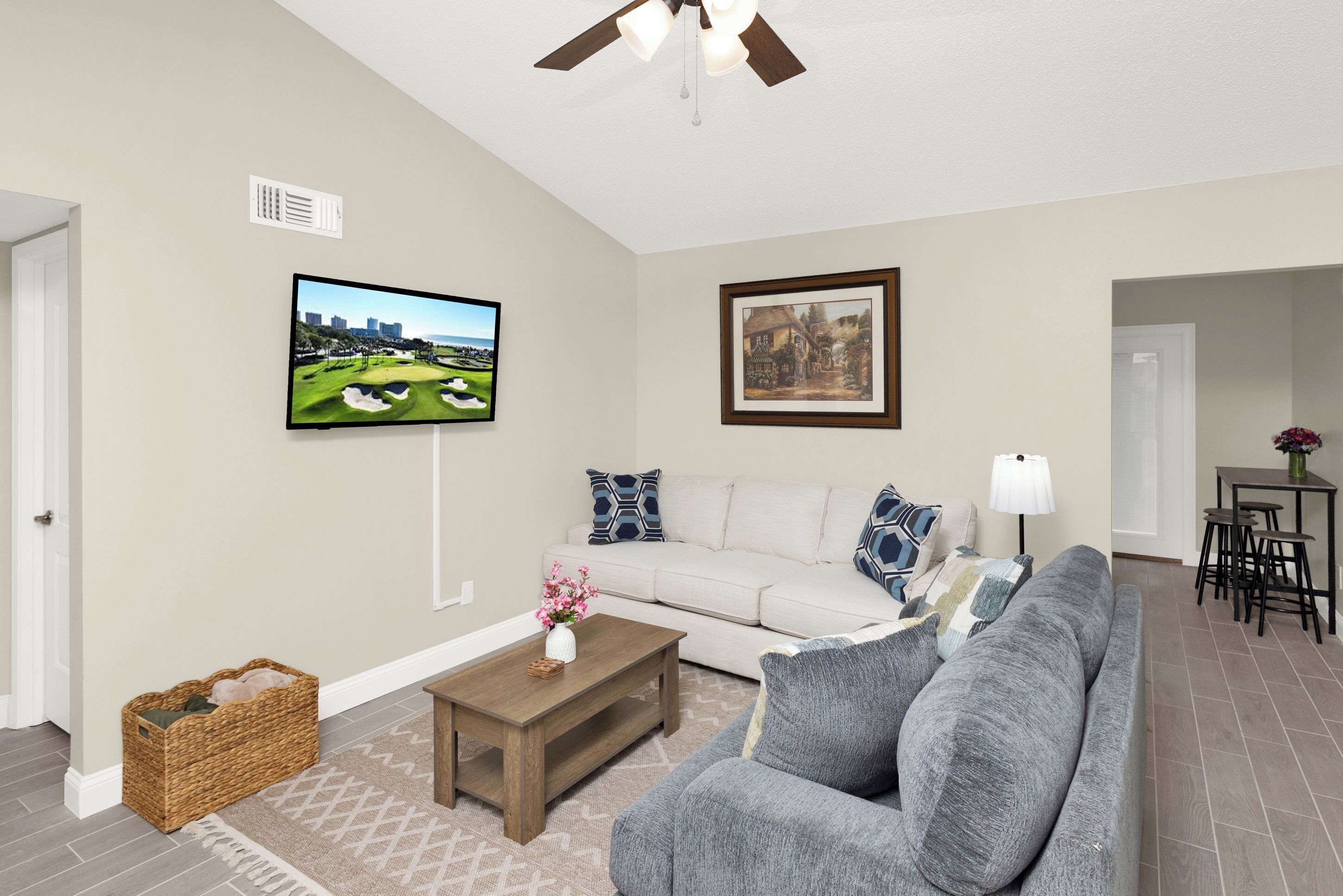 A living room with a gray sofa, a wooden coffee table, a TV, and a framed picture on the wall.
