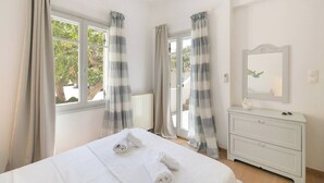 A bedroom with a bed, a dresser, a mirror, and curtains. - Naousa | 2BR House in the Heart of Town | Citrine (Naousa)