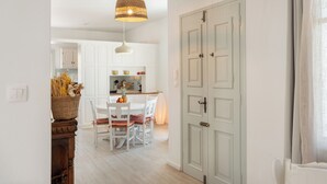 A bright kitchen with white cabinets, a dining table with chairs, and a basket of bread on a wooden stand. - Naousa | 2BR House in the Heart of Town | Citrine (Naousa)