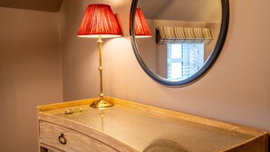 A wooden vanity with a gold lamp and a round mirror.