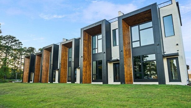 Un edificio moderno de varios pisos con techo plano, ventanas amplias y un césped.