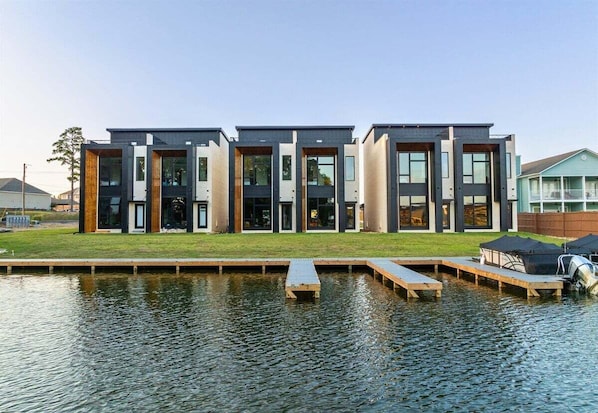 A modern building with a flat roof, large windows, and a dock extending into a body of water.