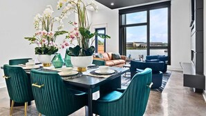 Un comedor moderno con una mesa dispuesta para cuatro personas, sillas color turquesa y un amplio ventanal con vistas al exterior.