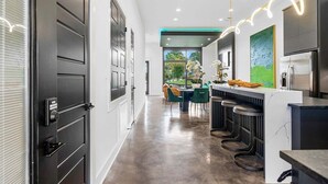 Una cocina moderna con barra, una mesa de comedor y sillas, y vistas al exterior.
