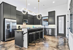 The kitchen's open-concept design features bold lighting, high-end appliances, and a layout that's perfect for entertaining or family gatherings.