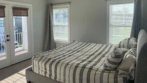 Un dormitorio con cama, ventilador de techo y vista a un espacio exterior a través de una puerta.