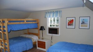 A room with bunk beds, a small bedside table with a lamp, and two framed pictures on the wall. - Captain's Quarters Cottage at Dockside Guest Quarters in York Harbor,  Maine. (YORK)