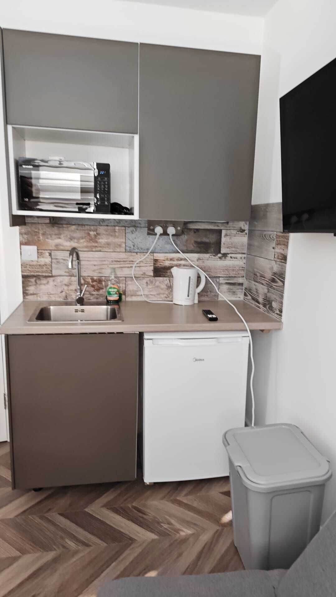 A compact kitchen with a built-in dishwasher, a sink, and a small refrigerator.