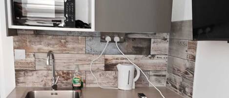 A compact kitchen with a built-in dishwasher, a sink, and a small refrigerator.