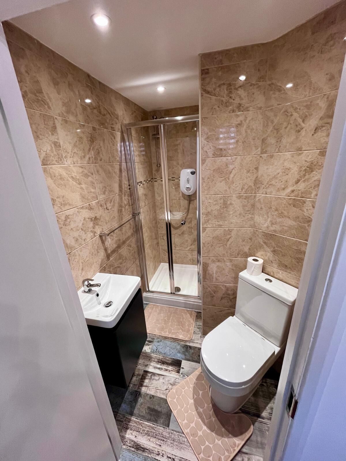 A modern bathroom with a glass-enclosed shower, a white sink, and a toilet.