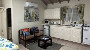 Una cocina compacta con armarios blancos, un microondas, una estufa y un comedor con dos sillas y una mesa.
