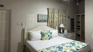 Een slaapkamer met een bed, een plafondventilator, een bord aan de muur en een kledingkast.