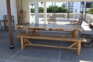 Enjoy dining or socializing in this outdoor patio area with a table and benches, surrounded by a view of the city and lush greenery.