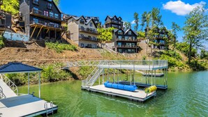 A lakeside property with multiple houses, a dock, and a bridge. - Stunning Mtn Lodge on Lake with two Story Dock, Indoor Pool, Arcade,and Hot Tub. (Sevierville)
