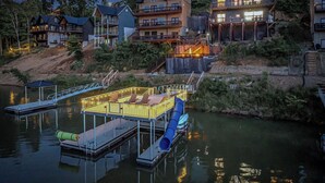 A lakeside property with multiple houses, a dock, and a water slide. - Stunning Mtn Lodge on Lake with two Story Dock, Indoor Pool, Arcade,and Hot Tub. (Sevierville)