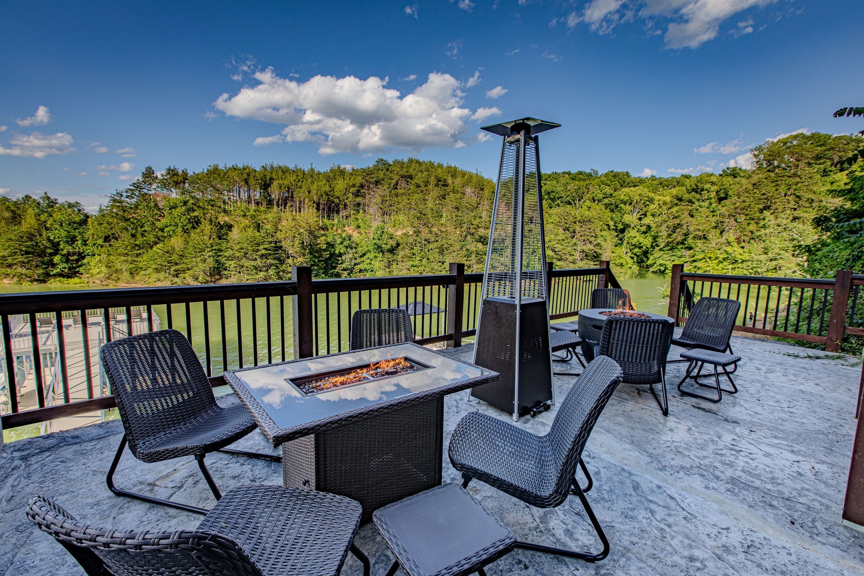 An outdoor patio with wicker furniture, a fire pit, and a view of a forested area.