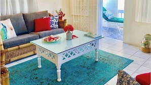 Una sala de estar con un sofá, una mesa de centro de vidrio y una alfombra estampada.