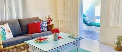 Una sala de estar con un sofá, una mesa de centro de vidrio y una alfombra estampada.