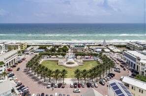 A coastal hotel with a central courtyard, parking area, and beach view.