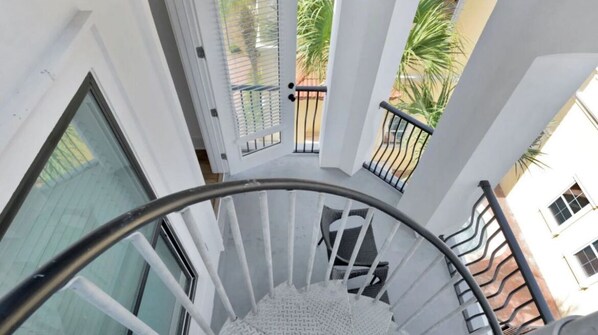 A spiral staircase with a metal handrail and white walls.