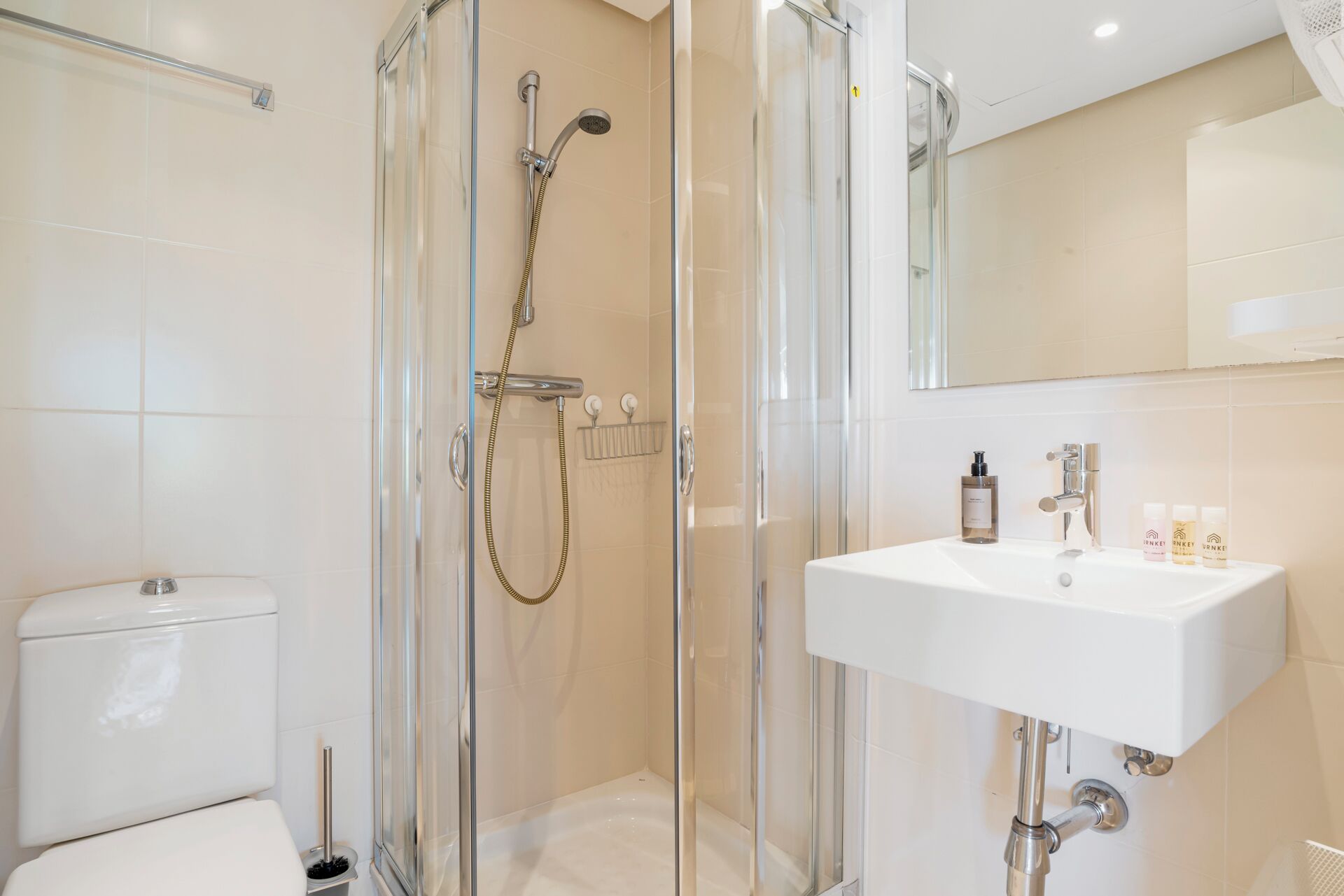 Une salle de bain moderne avec une douche à parois de verre, un lavabo blanc et des toilettes.